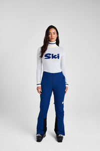 Person wearing a white ski sweater with 'Ski' logo and blue pants on a white background