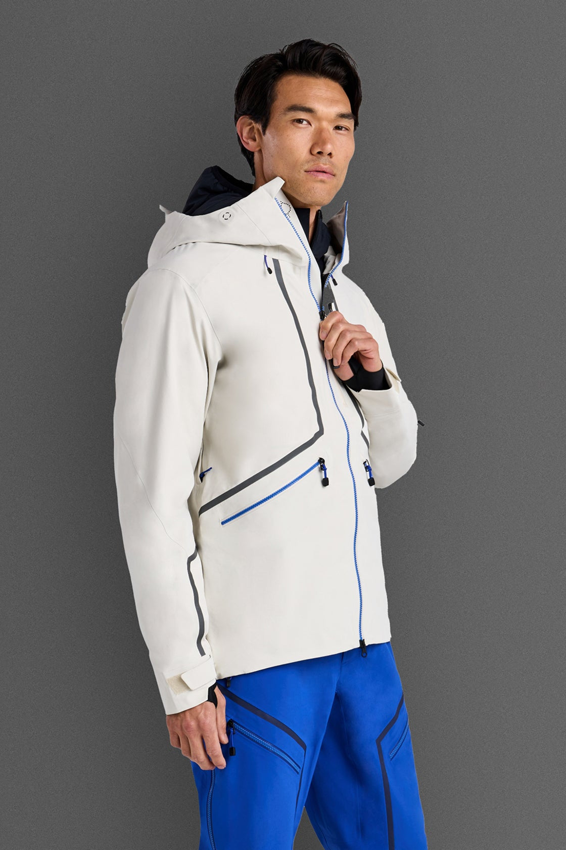 Person wearing a white jacket with blue accents on a gray background