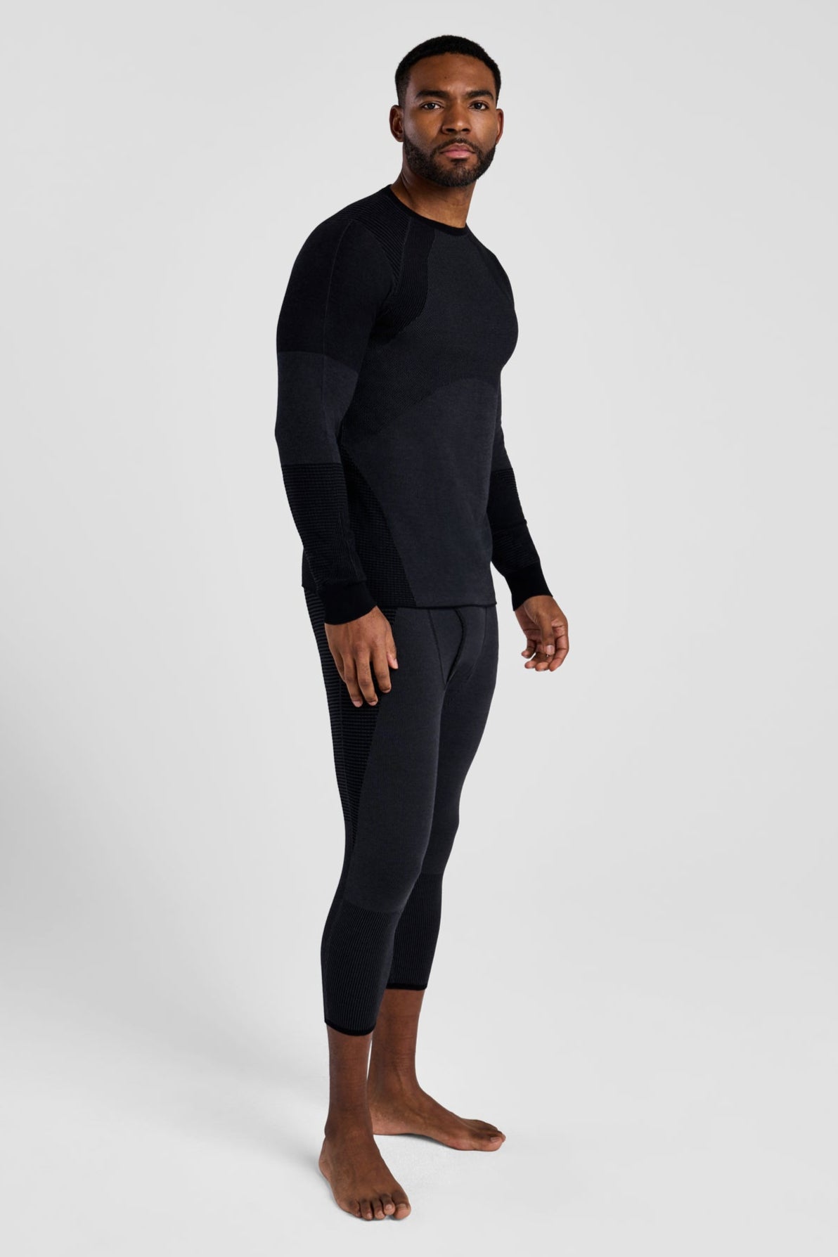 Man wearing a black long-sleeve shirt and black pants on a white background