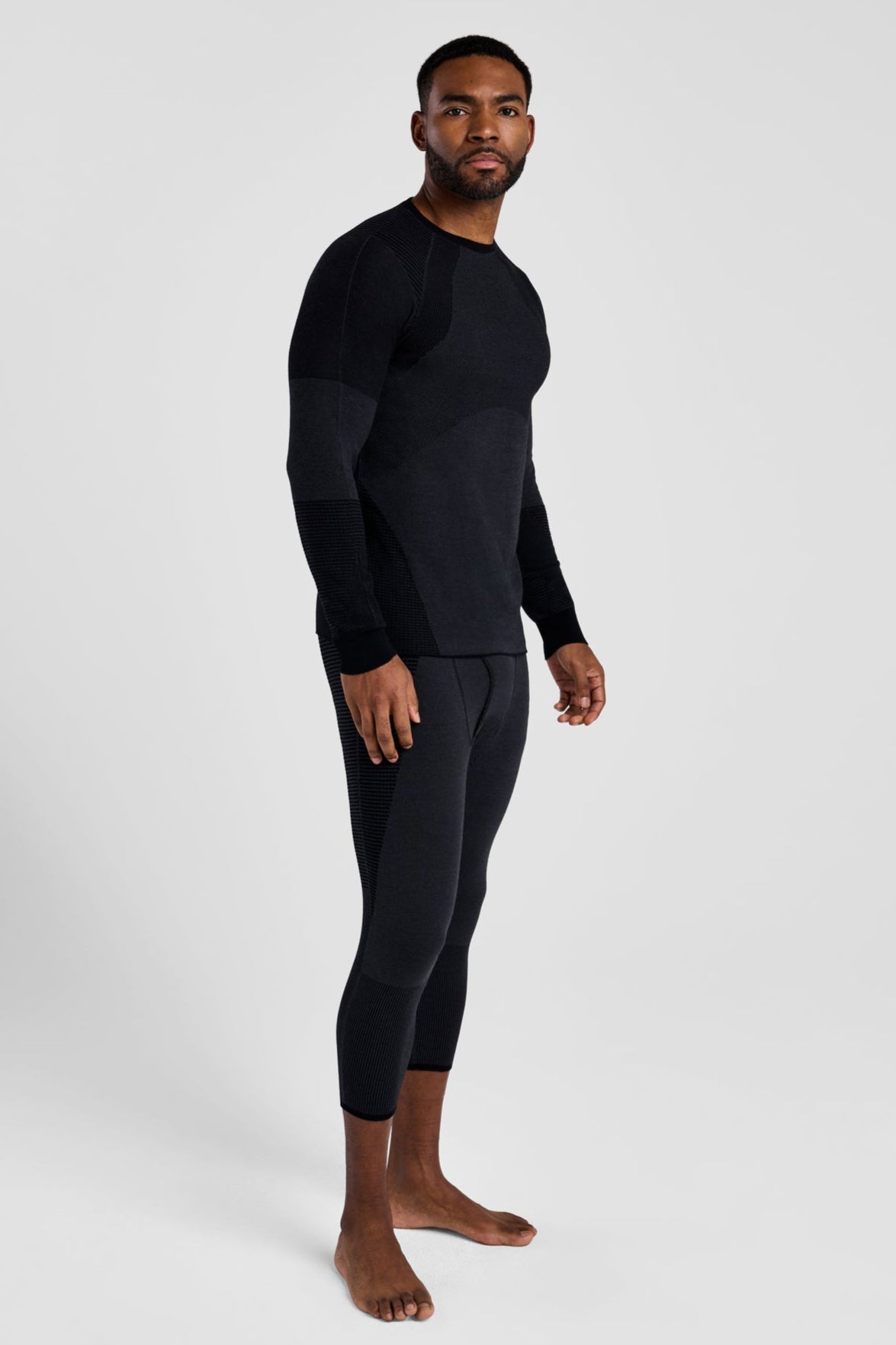 Man wearing a black long-sleeve shirt and black pants on a white background