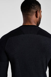 Person wearing a black textured sweater against a white background