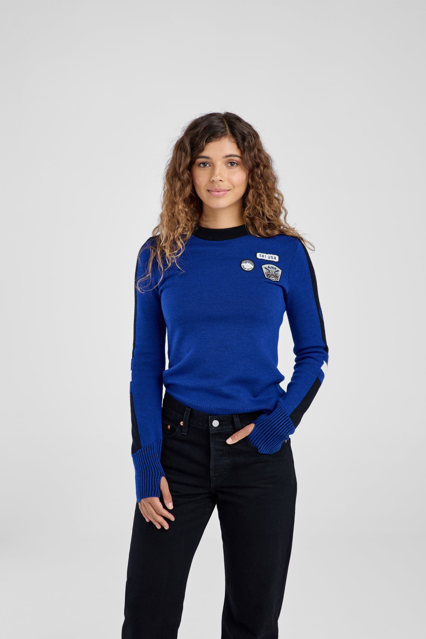 Woman wearing a blue sweater with black accents on a white background