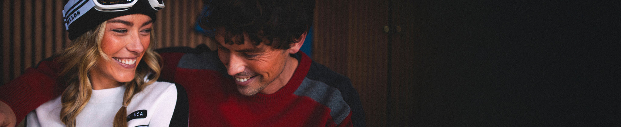 Two people smiling and looking at each other, with a dark background