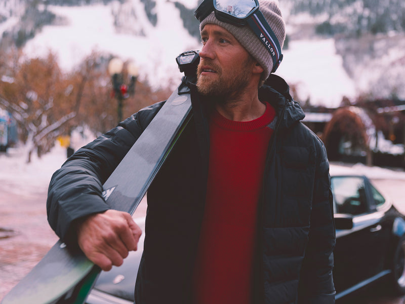 Man holding skis with a snowy landscape in the background