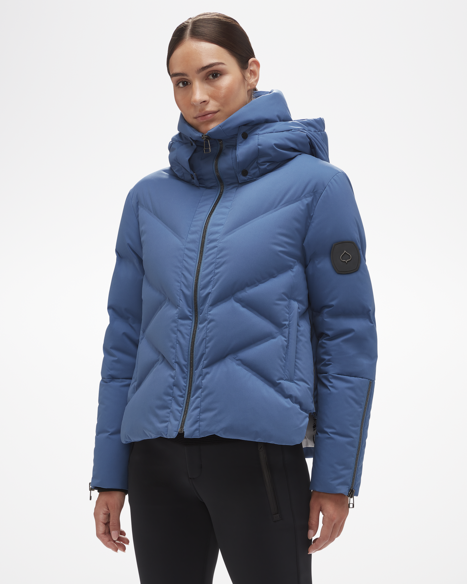 Cirque Down Jacket by Aspen Collection, modeled to female to show cut of jacket. Dark blue with black logo leaf and zipper, tall hood and neck protection