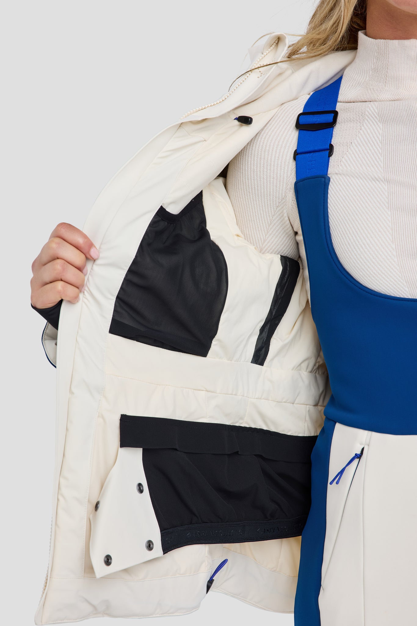 Person wearing a white jacket with black accents on a plain background