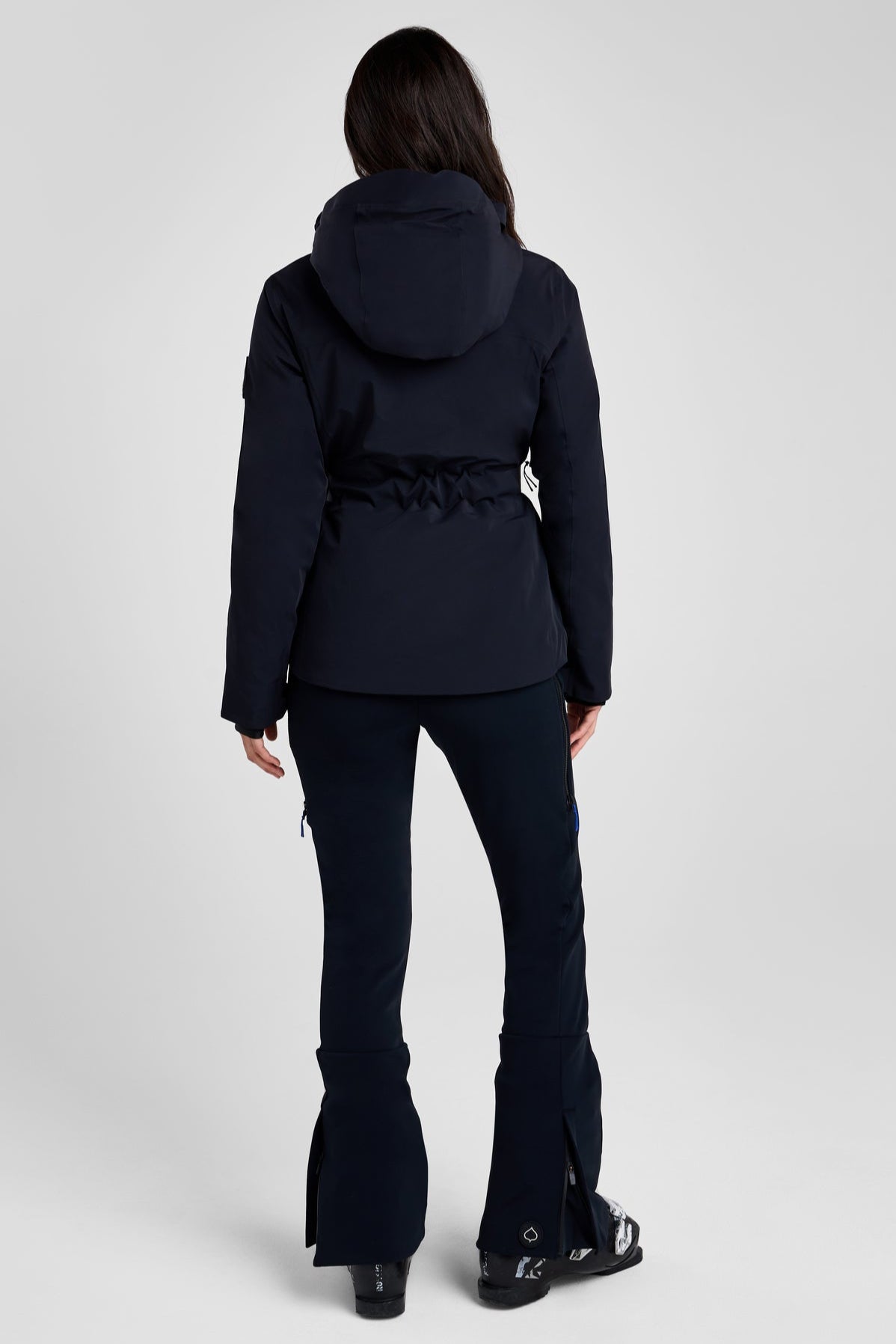 Person wearing a black ski jacket and pants on a white background