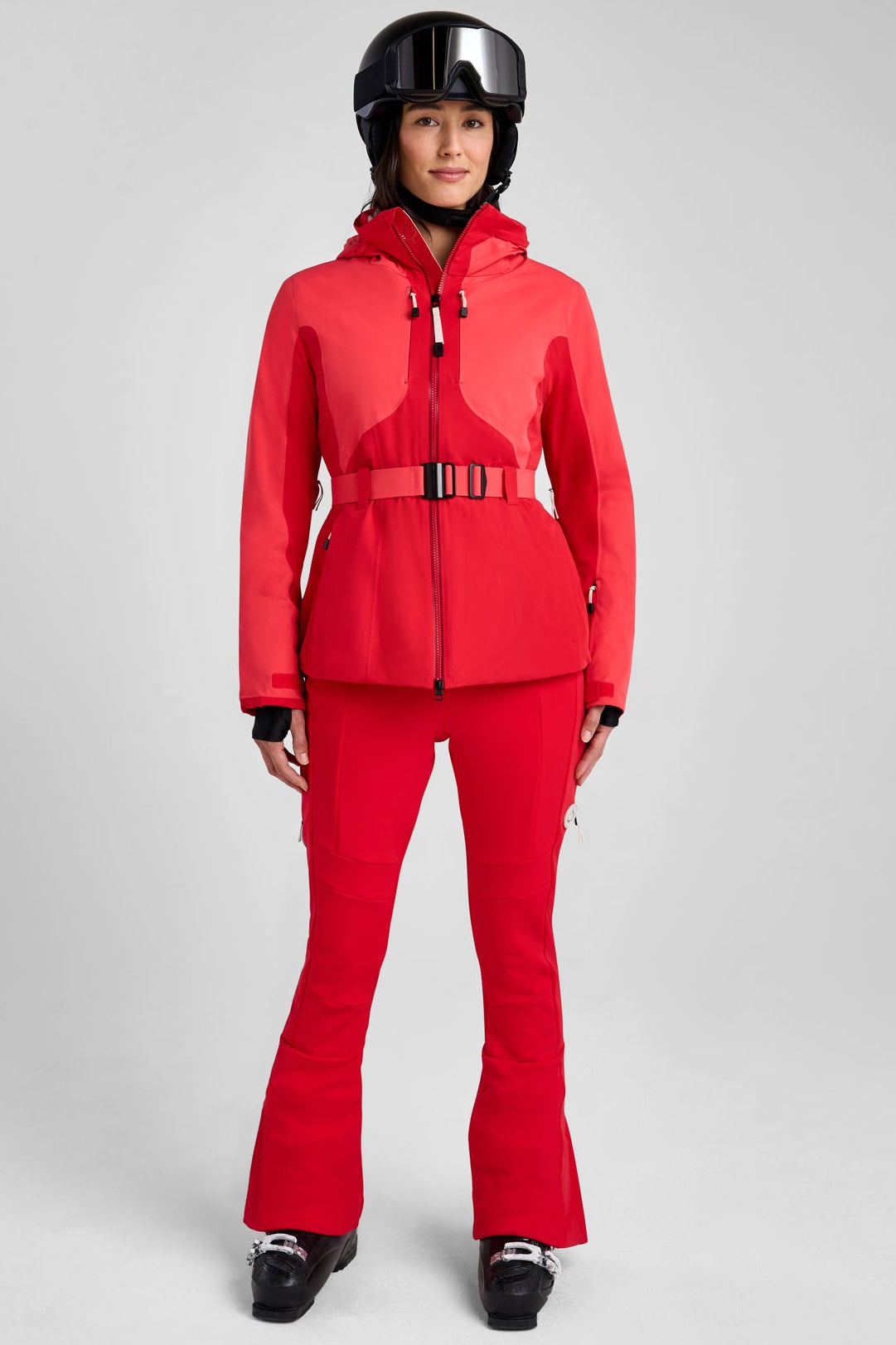 Person wearing a red snowsuit with a helmet on a gray background