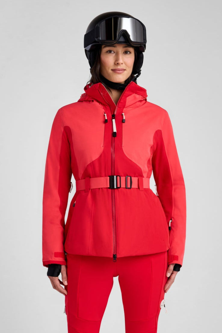 Person wearing a red snowsuit with a helmet on a gray background