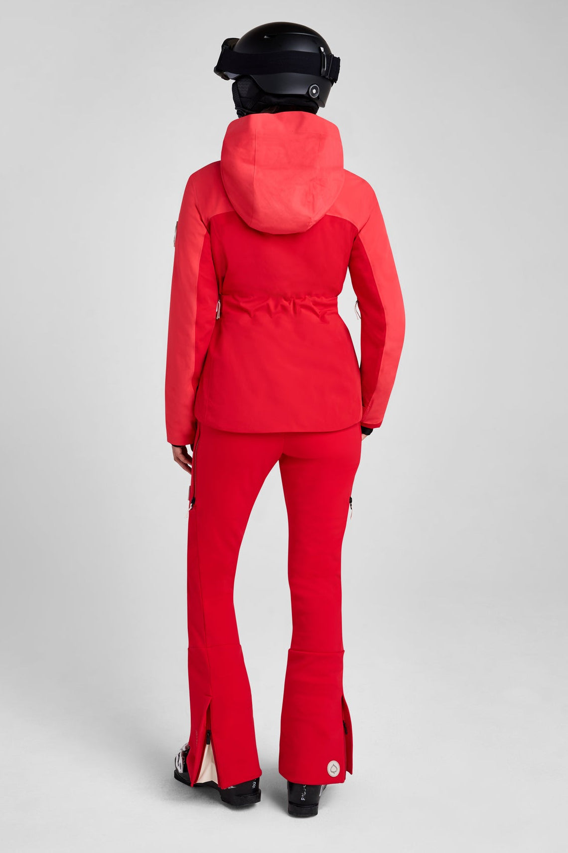 Person wearing a red ski suit and helmet on a gray background