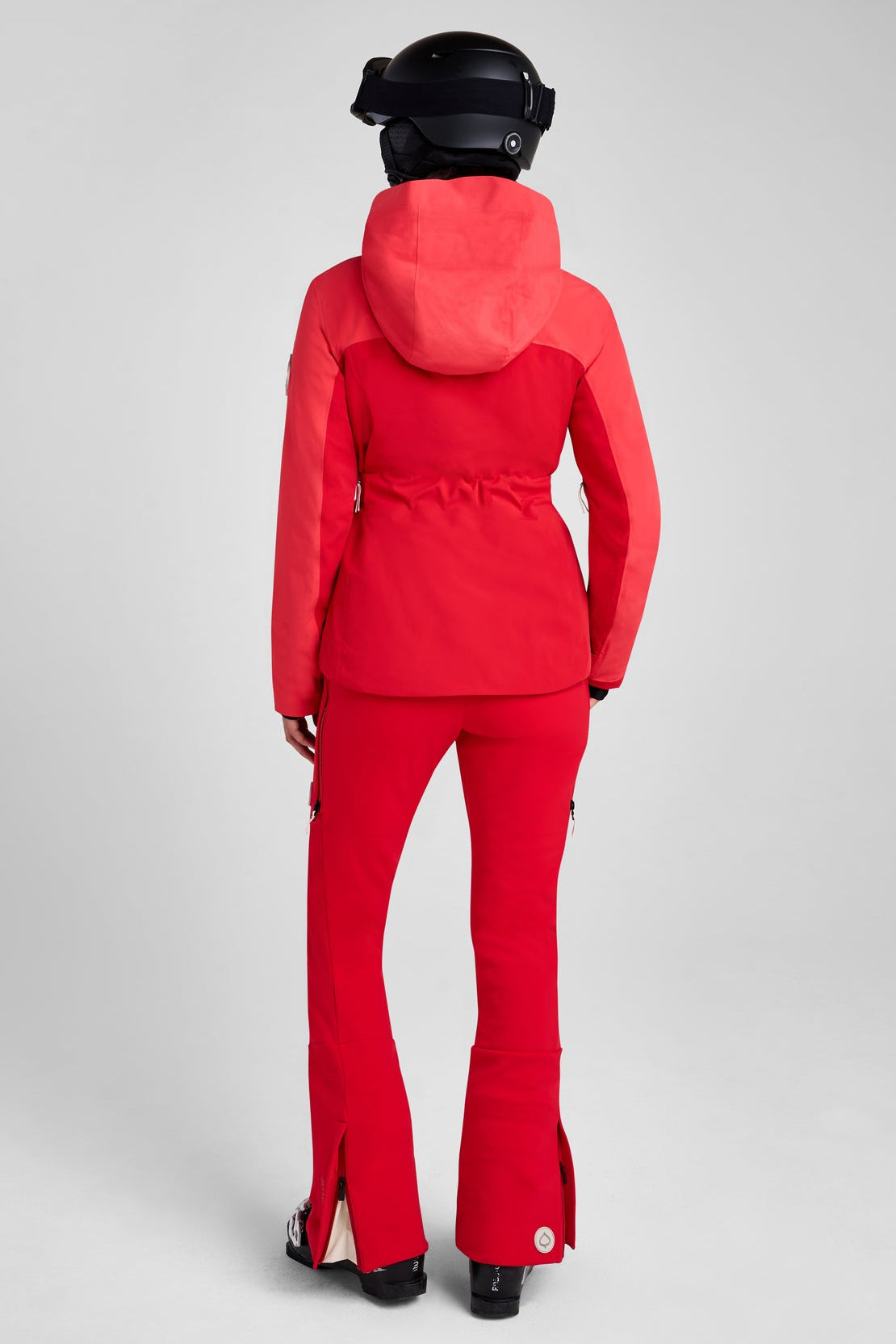 Person wearing a red ski suit and helmet on a gray background