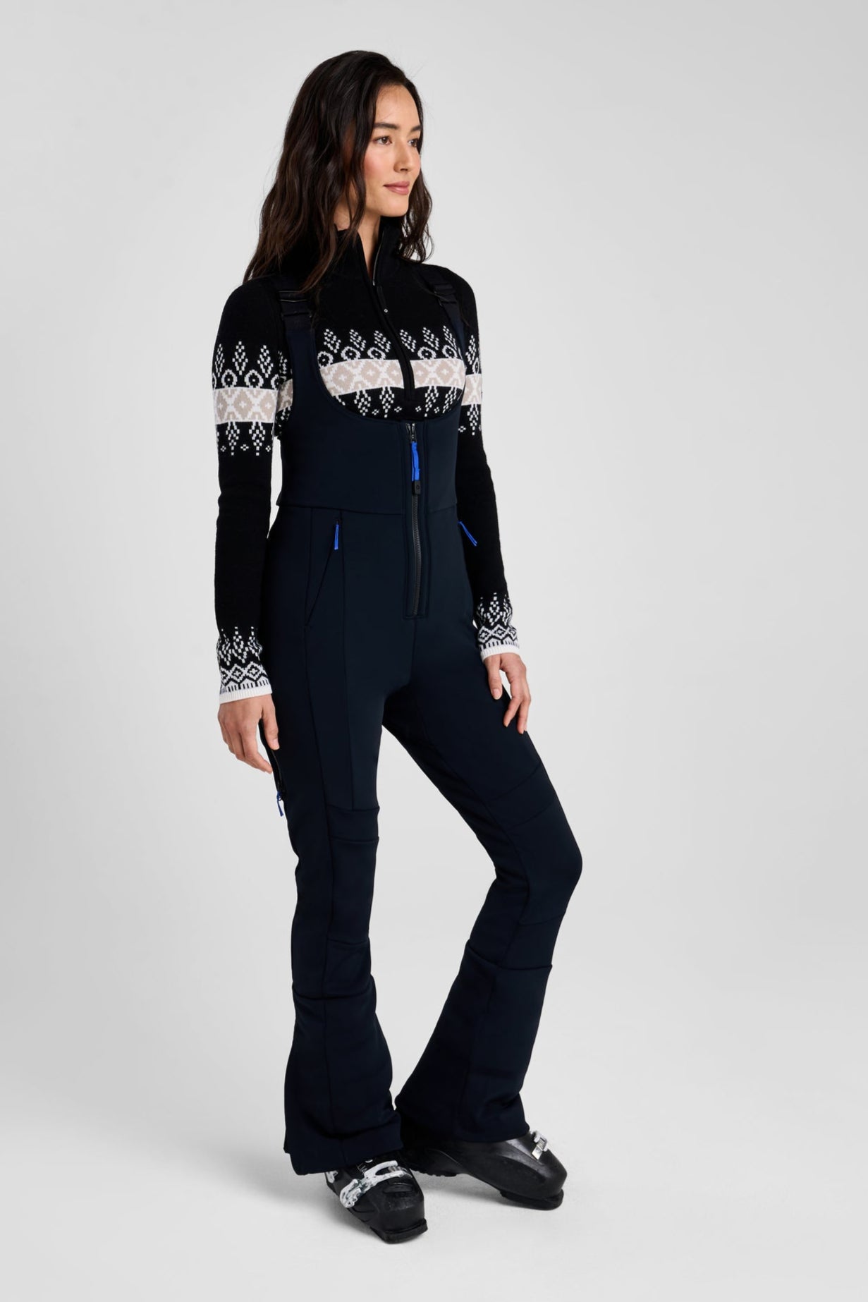 Woman wearing a black ski suit with white patterns on a gray background