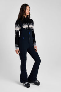 Woman wearing a black ski suit with white patterns on a gray background