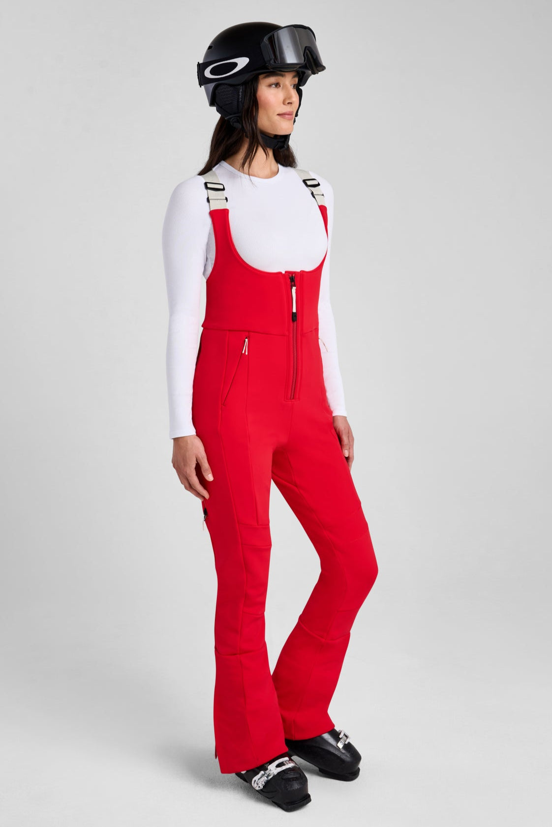 Person wearing red ski pants and a helmet on a gray background