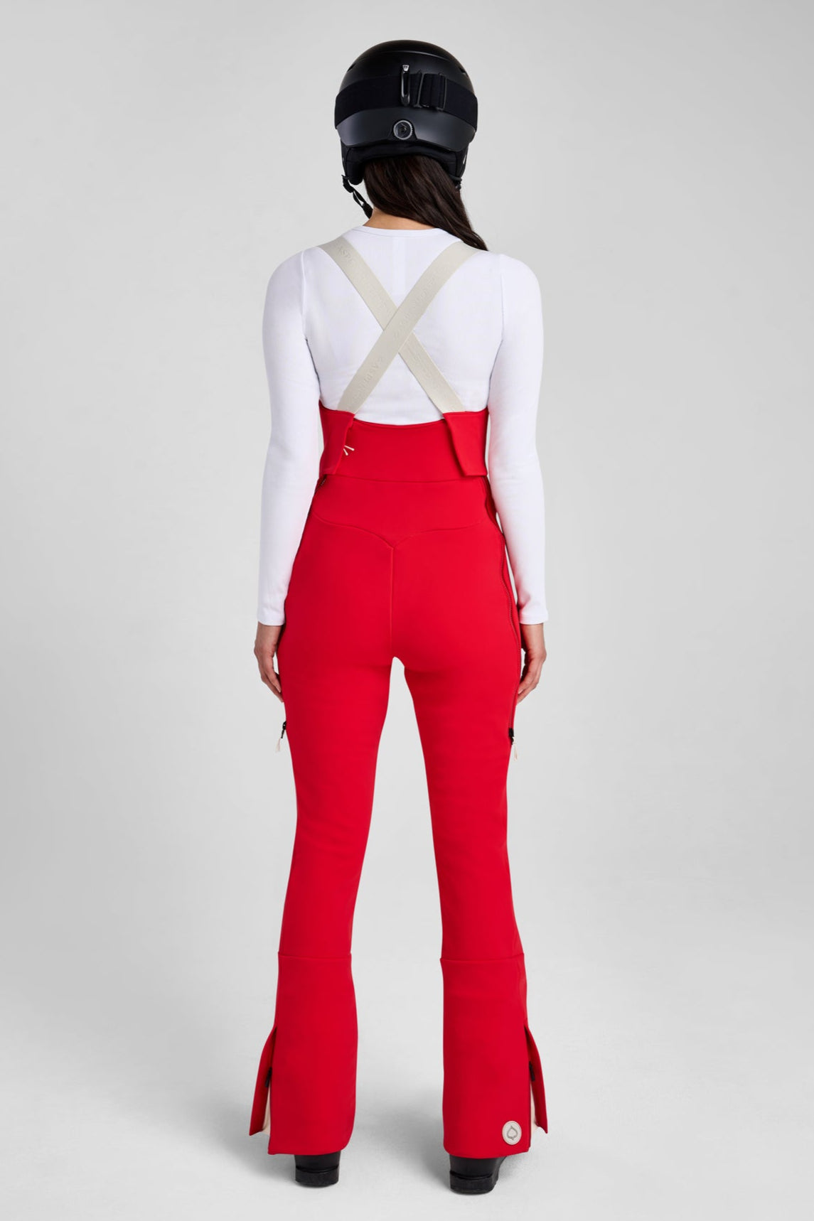 Person wearing red ski pants with a helmet on a white background