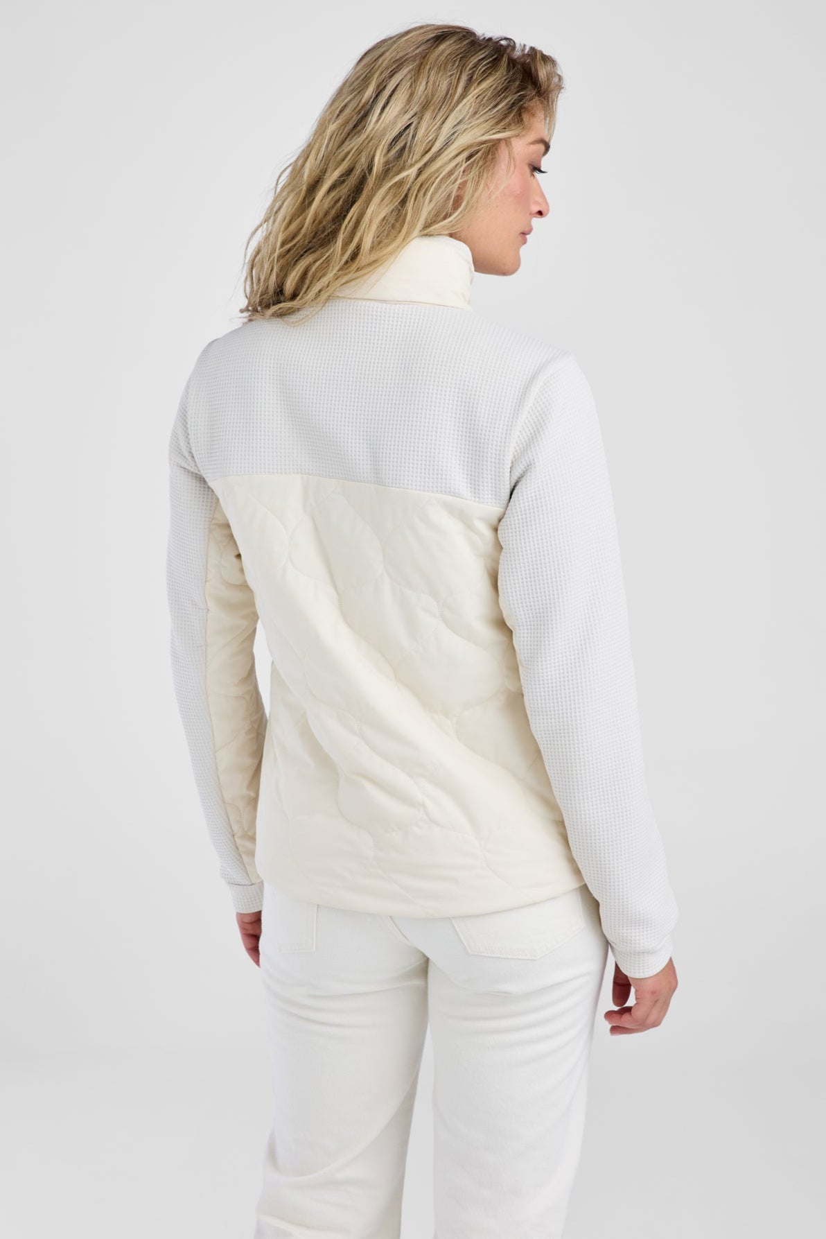 Woman wearing a white quilted jacket on a plain background