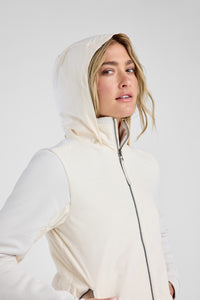 Woman wearing a white hooded jacket against a plain background