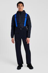 Person wearing a black snowsuit with blue suspenders on a white background