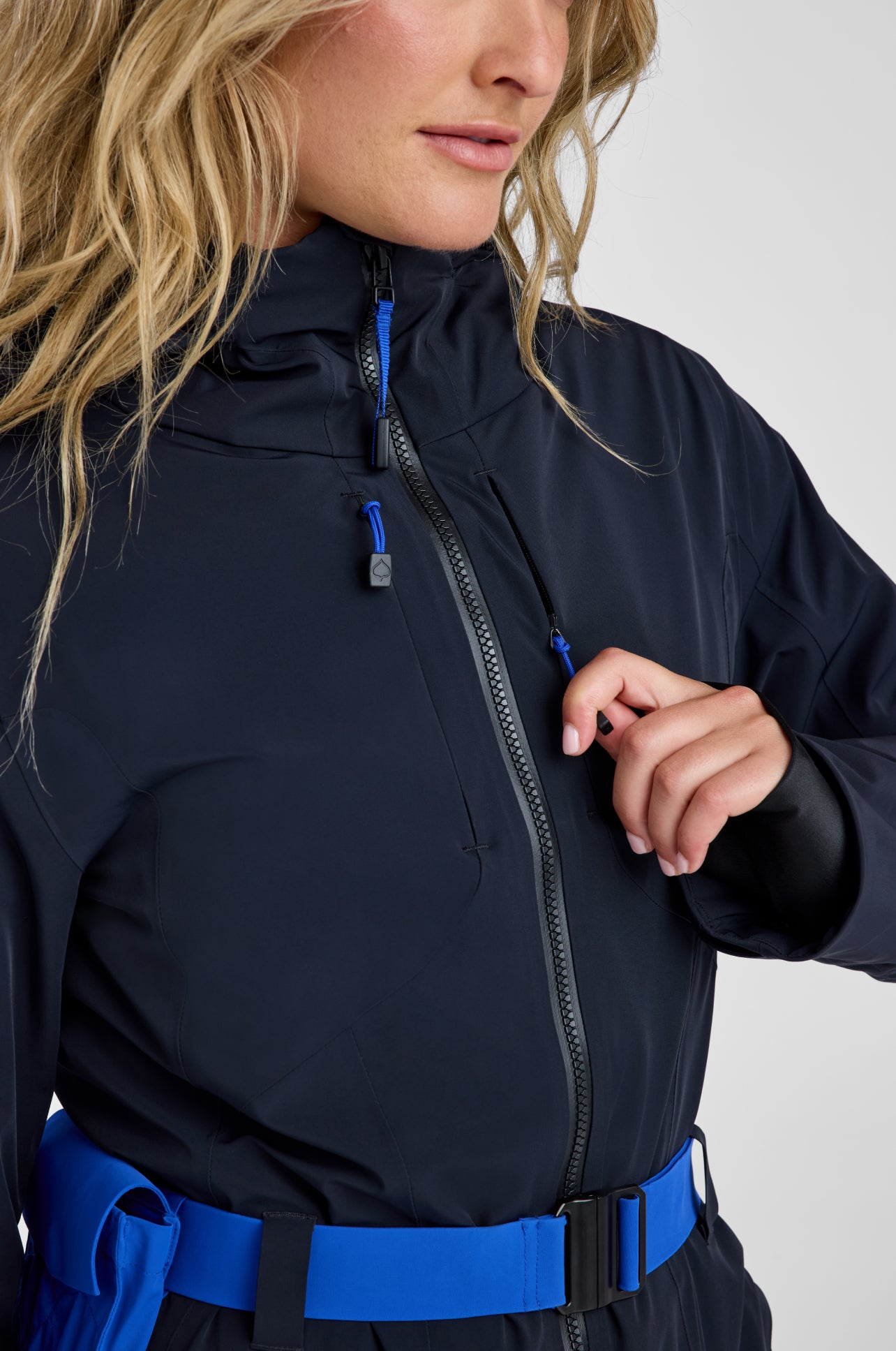 Person wearing a black jacket with blue accents on a white background