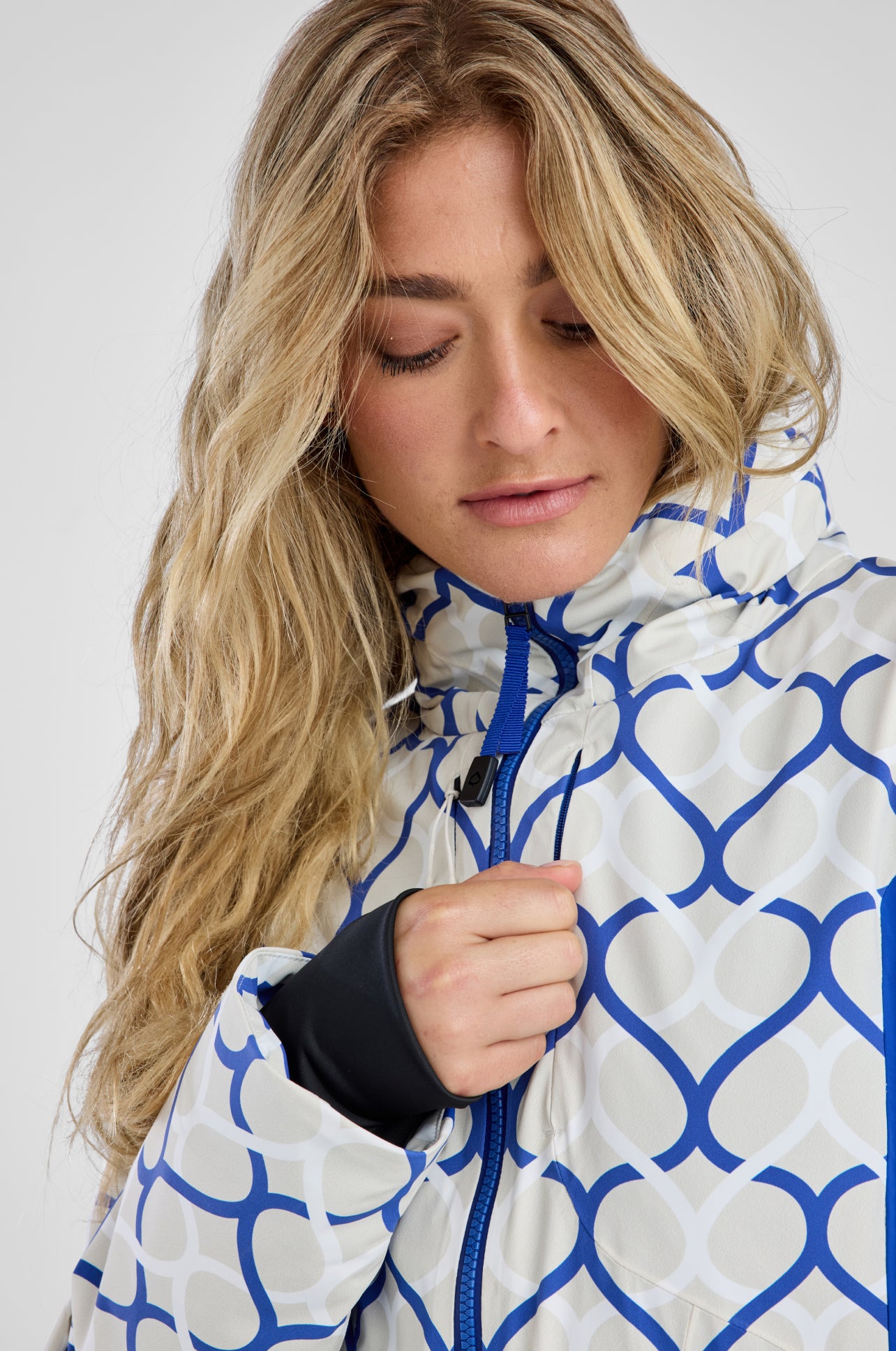 Person wearing a white and blue patterned jacket against a plain background