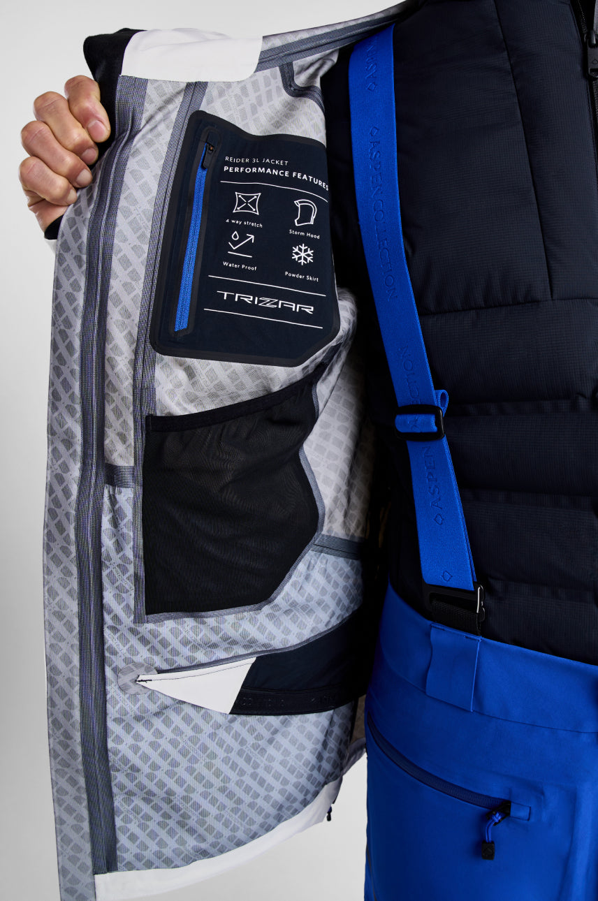 Close-up of a person holding a jacket with a visible brand label on a plain background