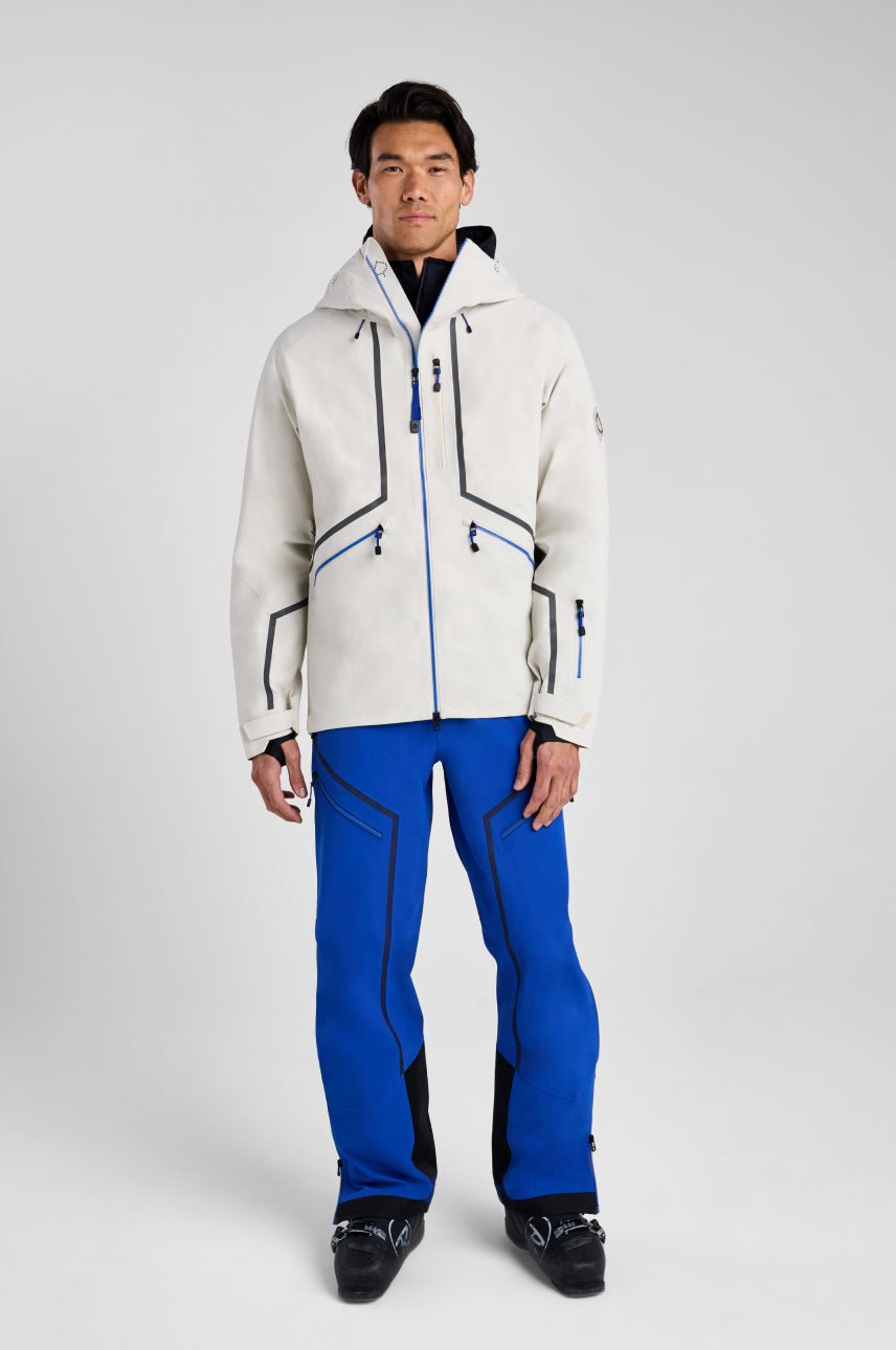 Person wearing a white ski jacket and blue pants on a gray background