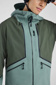 Person wearing a green and gray jacket with a helmet on a white background