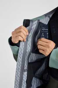 Close-up of a person opening a jacket with a brand logo on a light gray background