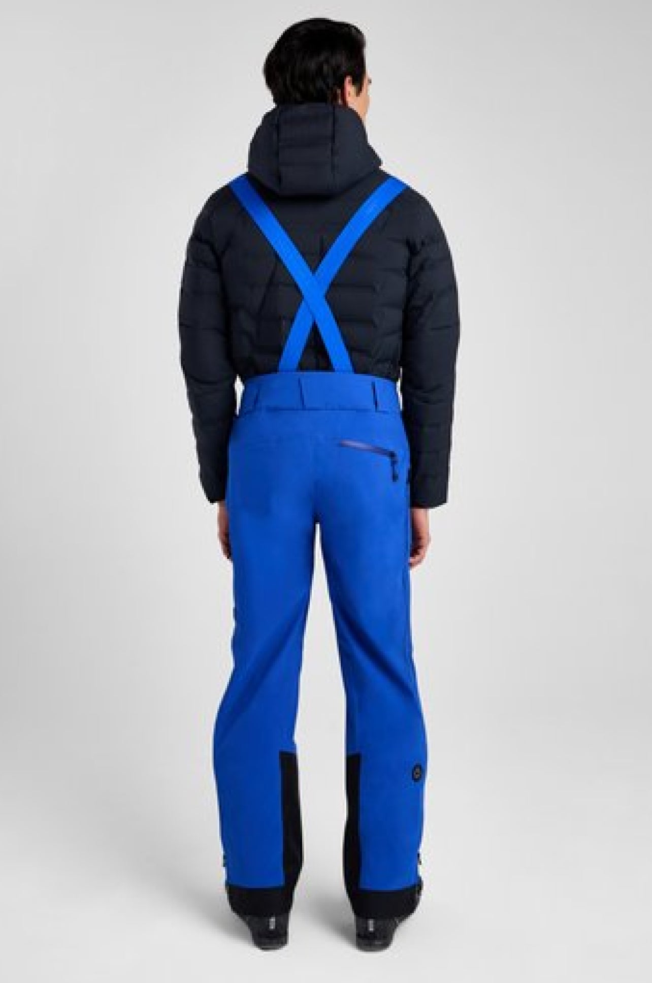 Person wearing a black jacket and blue pants on a white background
