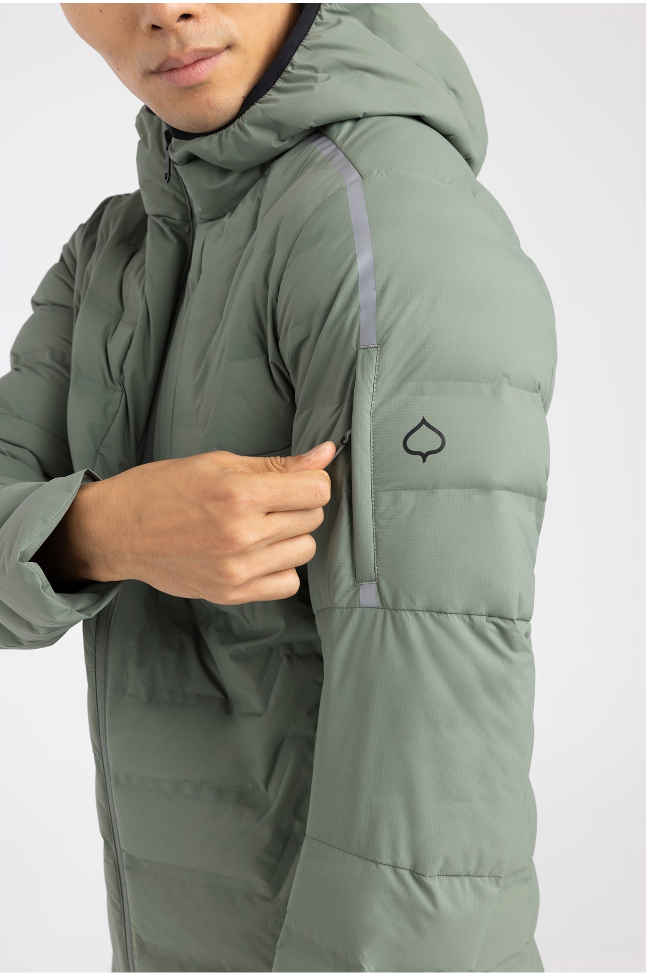 Person wearing a green puffer jacket with a leaf logo on a white background