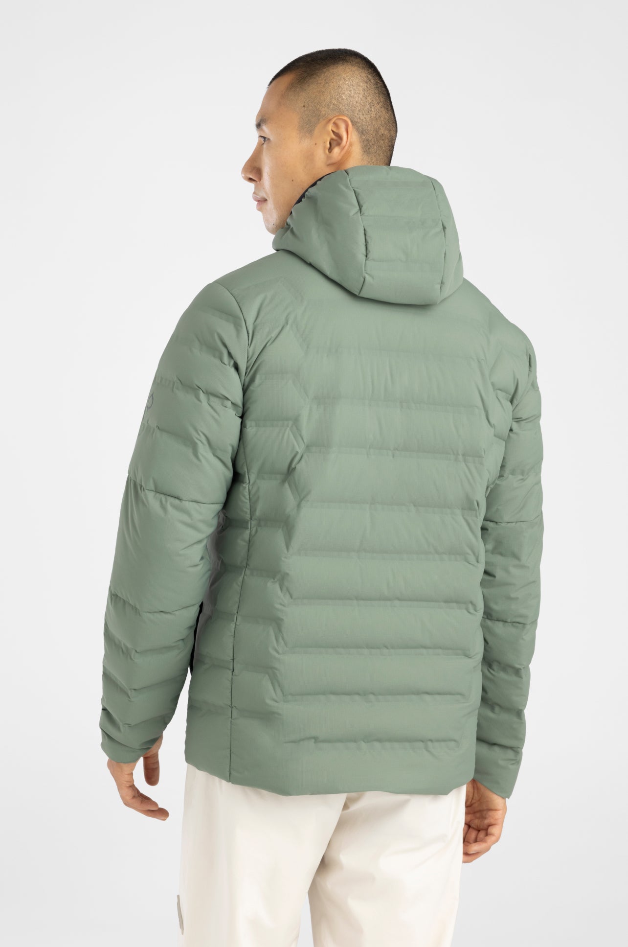 Person wearing a green puffer jacket on a white background