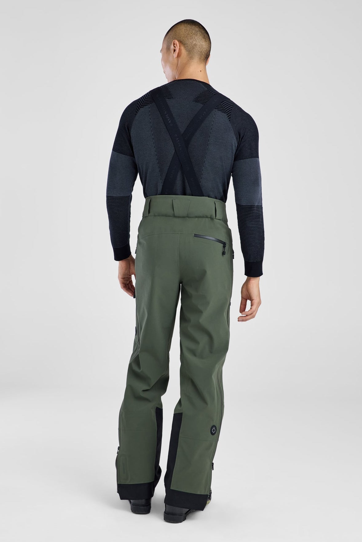 Person wearing a black top and green pants on a white background