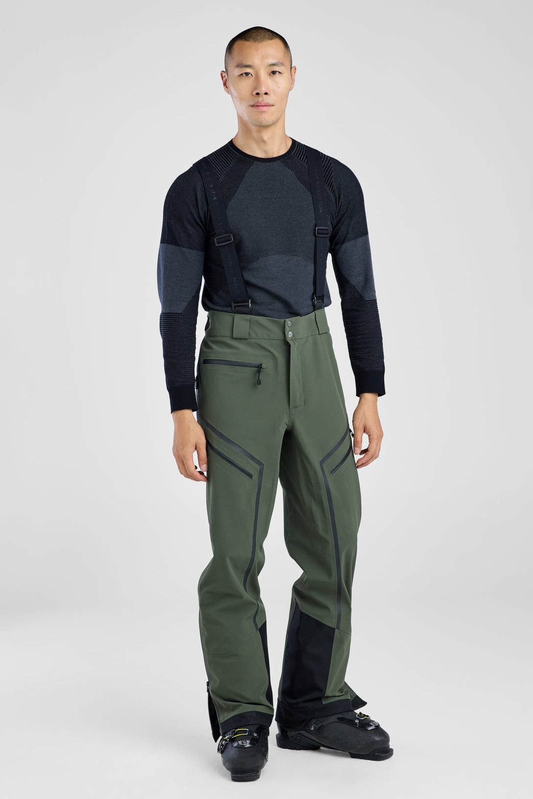Person wearing a black long-sleeve shirt and green pants on a white background