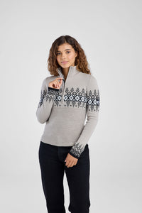 Woman wearing a gray sweater with black and white pattern on a light gray background