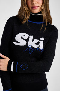 Black sweater with 'Ski Ajax' text worn by a person on a white background