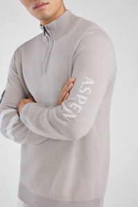 Person wearing a gray sweater with 'Aspen' branding on a white background