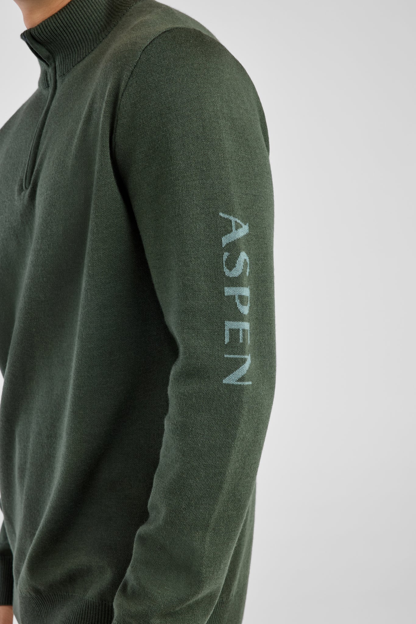Green sweater with 'Aspen' branding on a light gray background
