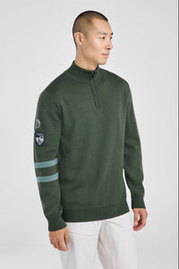 Man wearing a green sweater with a logo on a white background