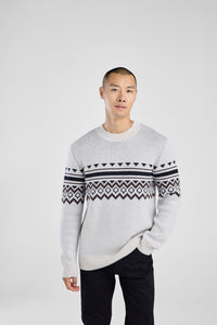 Man wearing a white sweater with a patterned design on a white background