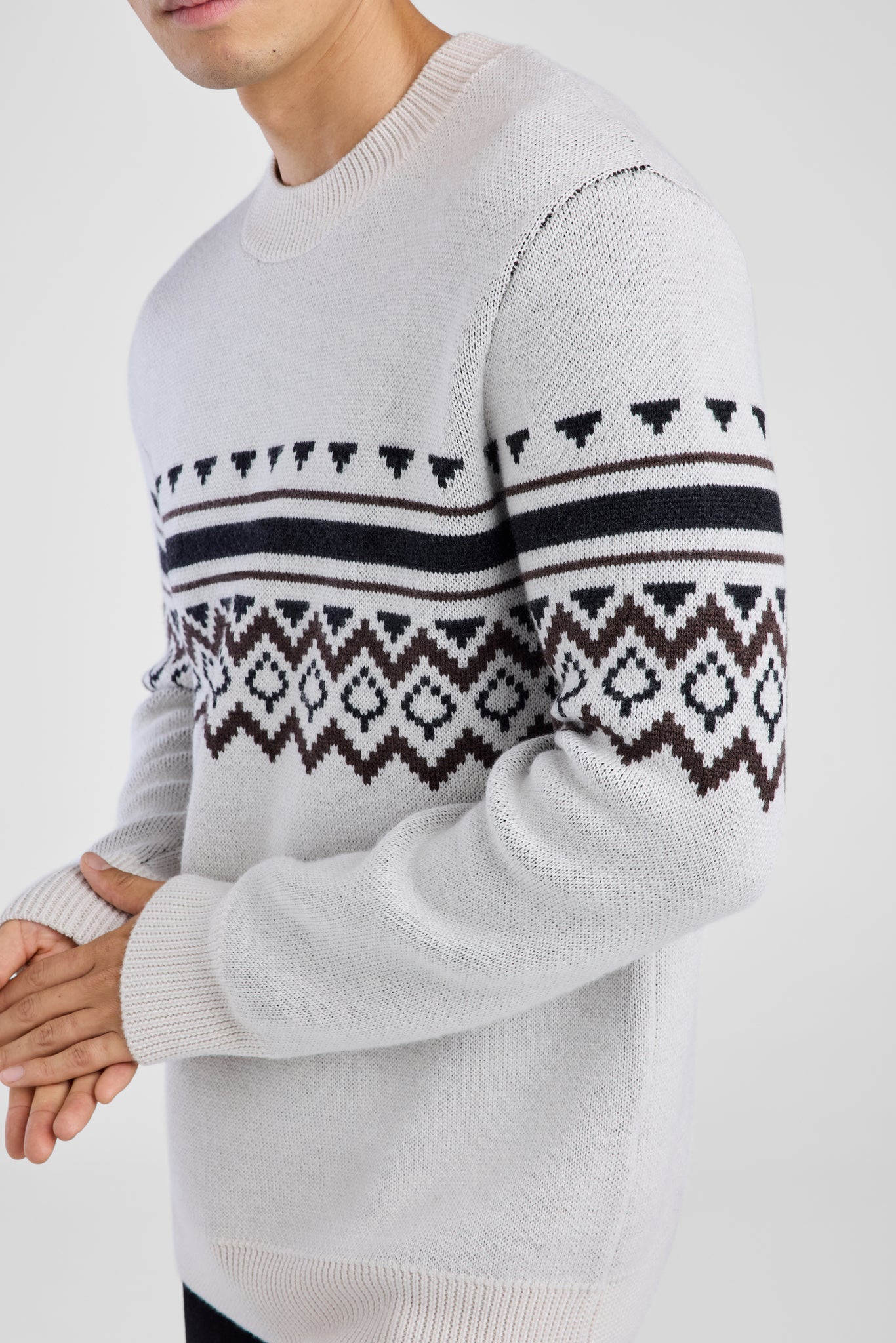Man wearing a white sweater with a patterned design on a white background
