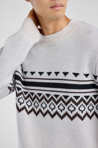 Man wearing a white sweater with a patterned design on a white background