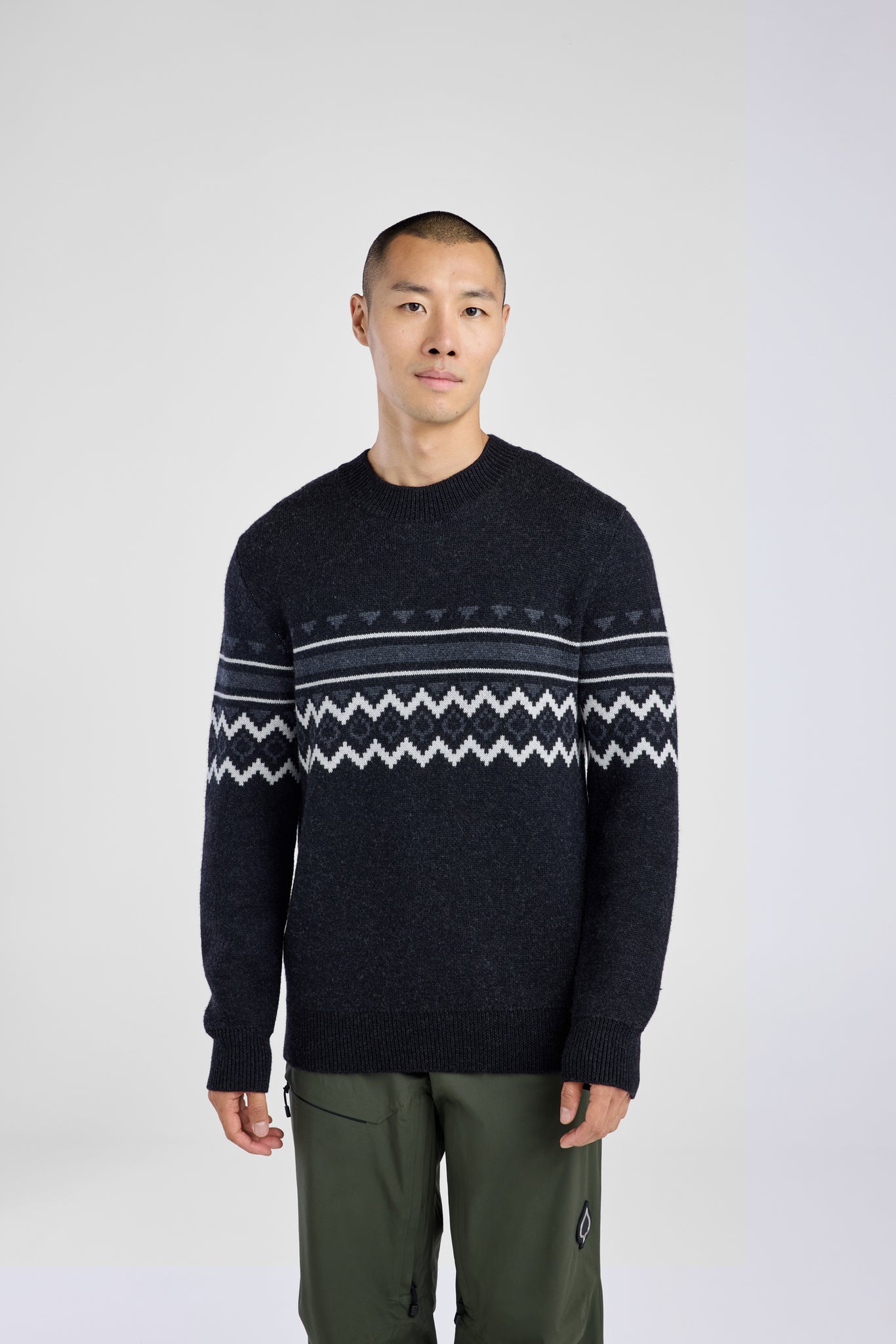 Man wearing a dark sweater with a patterned design on a white background