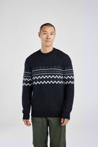 Man wearing a dark sweater with a patterned design on a white background