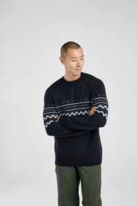 Man wearing a dark sweater with a patterned design on a white background