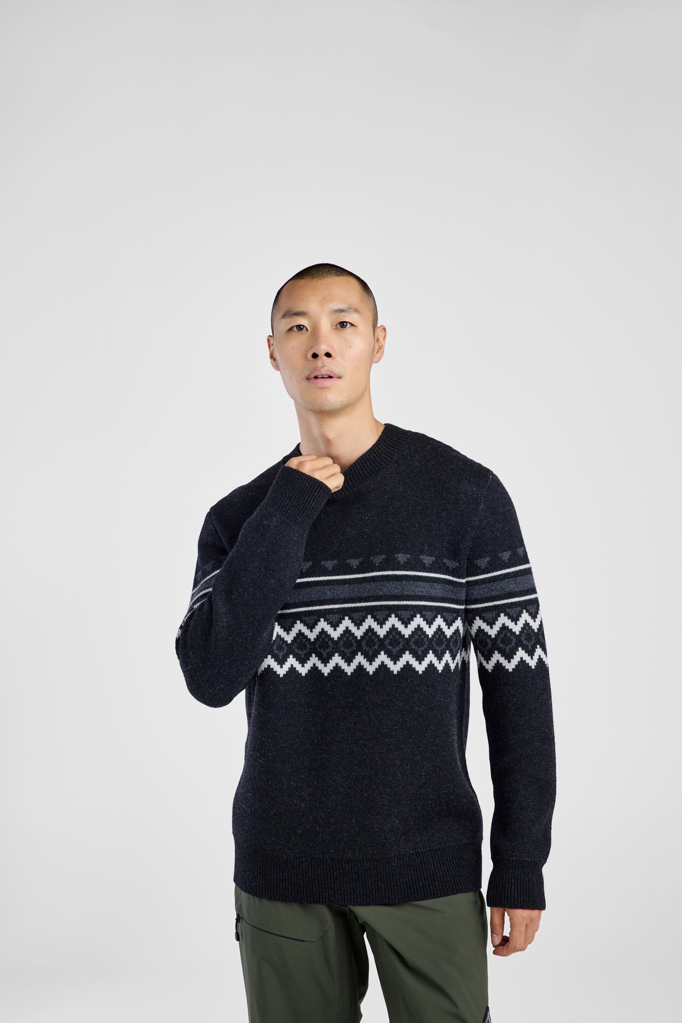 Man wearing a dark sweater with a patterned design on a white background