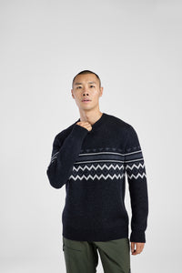 Man wearing a dark sweater with a patterned design on a white background