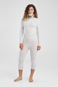 Person wearing a white long-sleeve top and white leggings on a white background