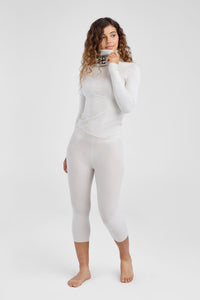 Woman wearing a white long-sleeve top and leggings on a white background
