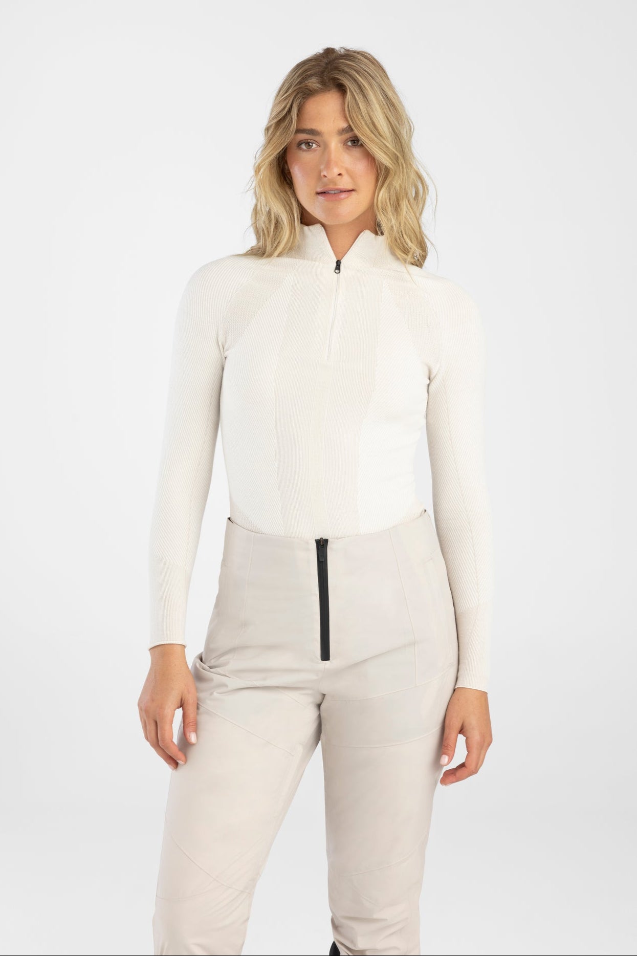 Woman wearing a white top and light gray pants on a white background