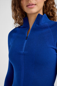 Close-up of a person wearing a blue ribbed baselayer on a light gray background